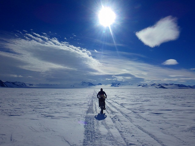 南極の輝く雪面を走る大島さん